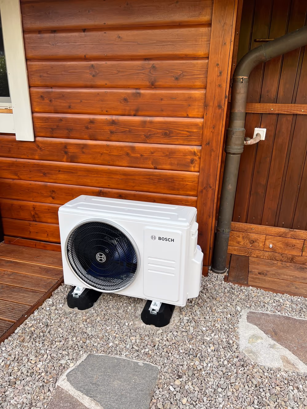 Bosch Klimaanlage auf Kiesbett vor Holzverkleidung